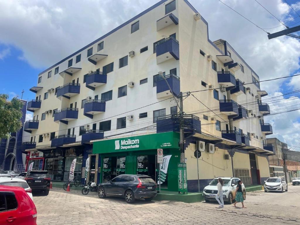 un gran edificio con coches estacionados frente a él en Apartamento 2 quartos, en Teixeira de Freitas