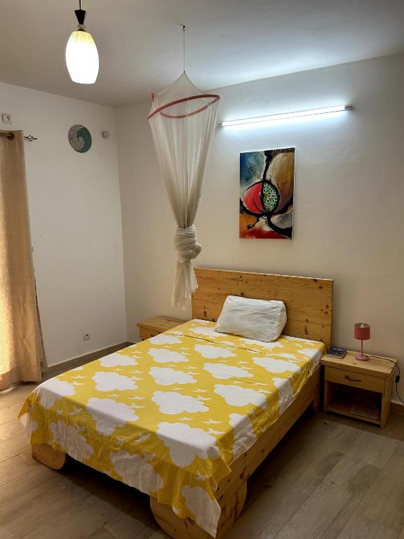 1 dormitorio con 1 cama con edredón amarillo en Chambre spacieuse avec balcon - salle de bain extérieure privée & breakfast en Saint-Louis
