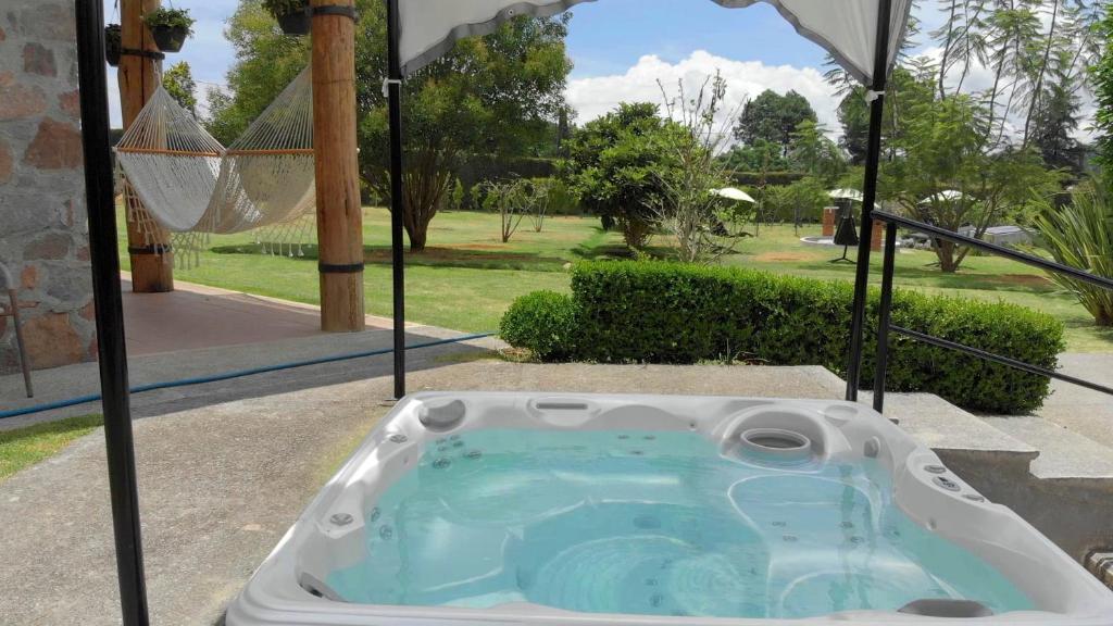 a jacuzzi tub in a backyard with an umbrella at Cabin Manzana Nature Retreat with amenities in Zitácuaro