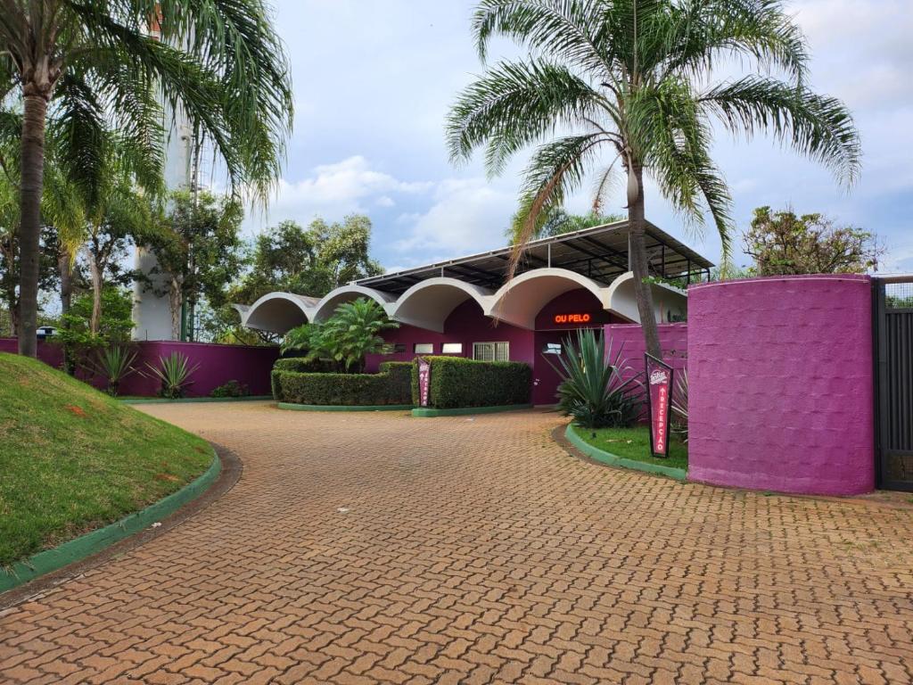 a building with purple walls and palm trees at Motel Deslize Limeira 2 in Limeira