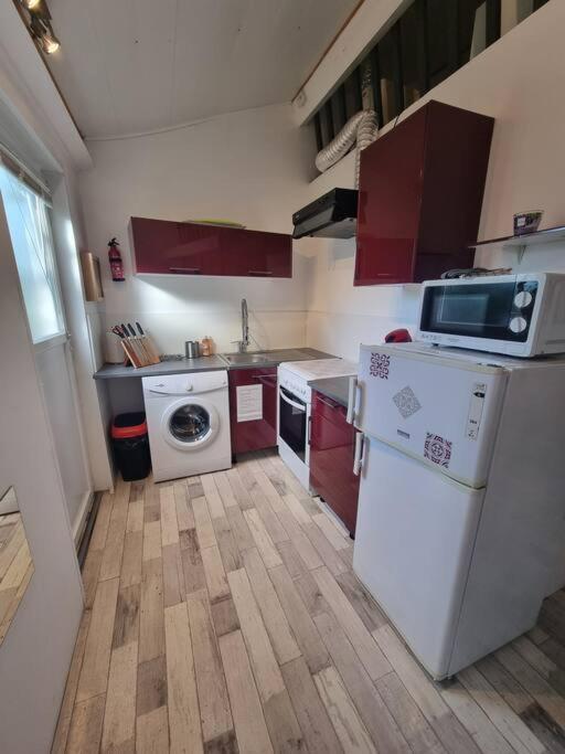 eine kleine Küche mit roten Schränken und weißen Geräten in der Unterkunft Le Guichard - Wifi - Parking - Terrasse in Clermont-Ferrand