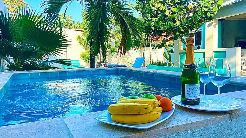 a plate of fruit and a bottle of wine next to a swimming pool at Beautiful and Spacious Mediterranean Style Villa on Palm Beach in Palm-Eagle Beach