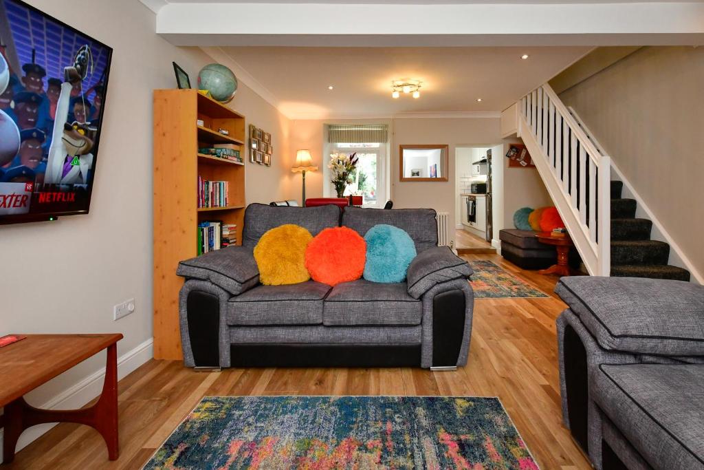 ein Wohnzimmer mit einem Sofa und bunten Kissen in der Unterkunft Rare Free Parking in Heart of the City - Highly Rated Townhouse & Garden - Peaceful Area Less Than 5min Walk to Beach, Shops, Bars, Arena, Marina, Parks in Swansea