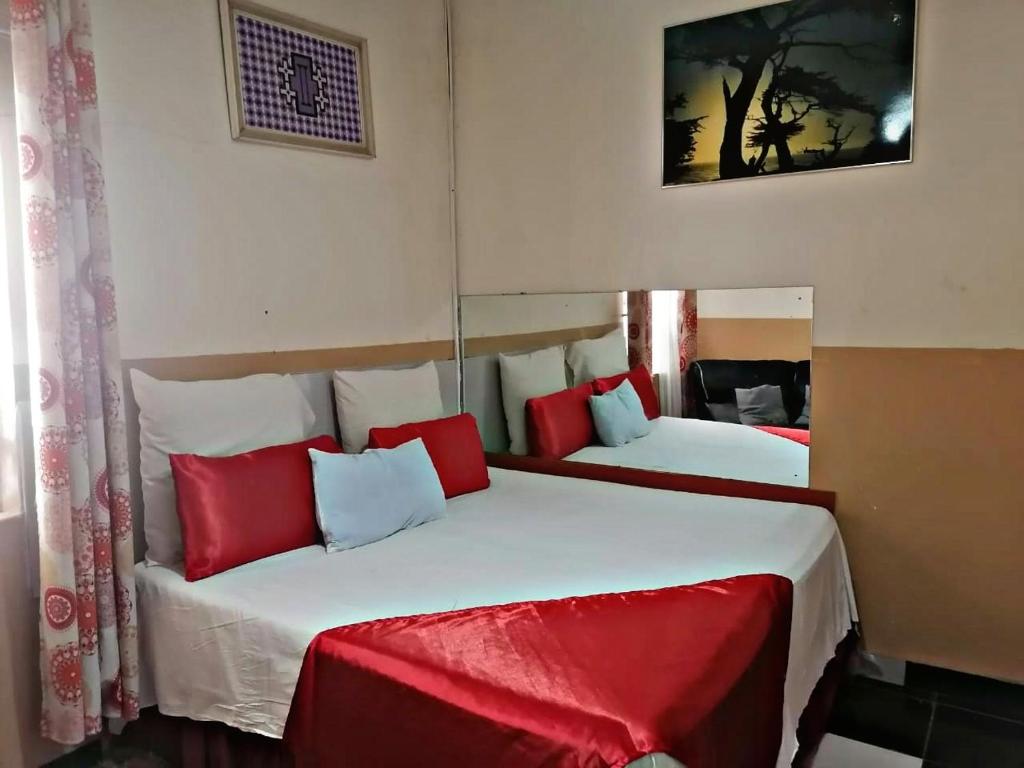 duas camas num quarto com vermelho e branco em Valleycenter guesthouse em Joanesburgo
