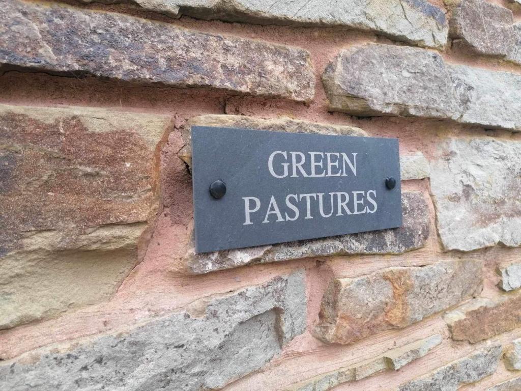 un cartel en una pared de ladrillo con las palabras "pastos verdes" en Green Pasture, en Much Birch