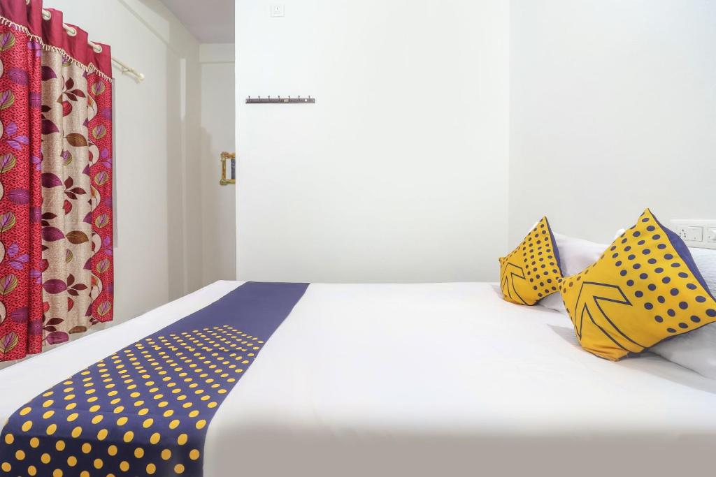 a bed with yellow and blue polka dot pillows on it at SPOT ON Rohini Inn Kadampuzha in Kottakkal