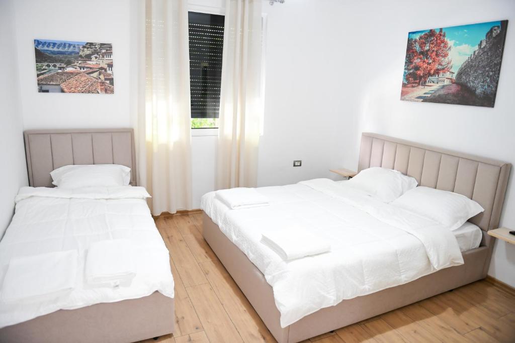 2 Betten in einem Schlafzimmer mit weißen Wänden und Holzböden in der Unterkunft Hotel Villa Edis in Berat