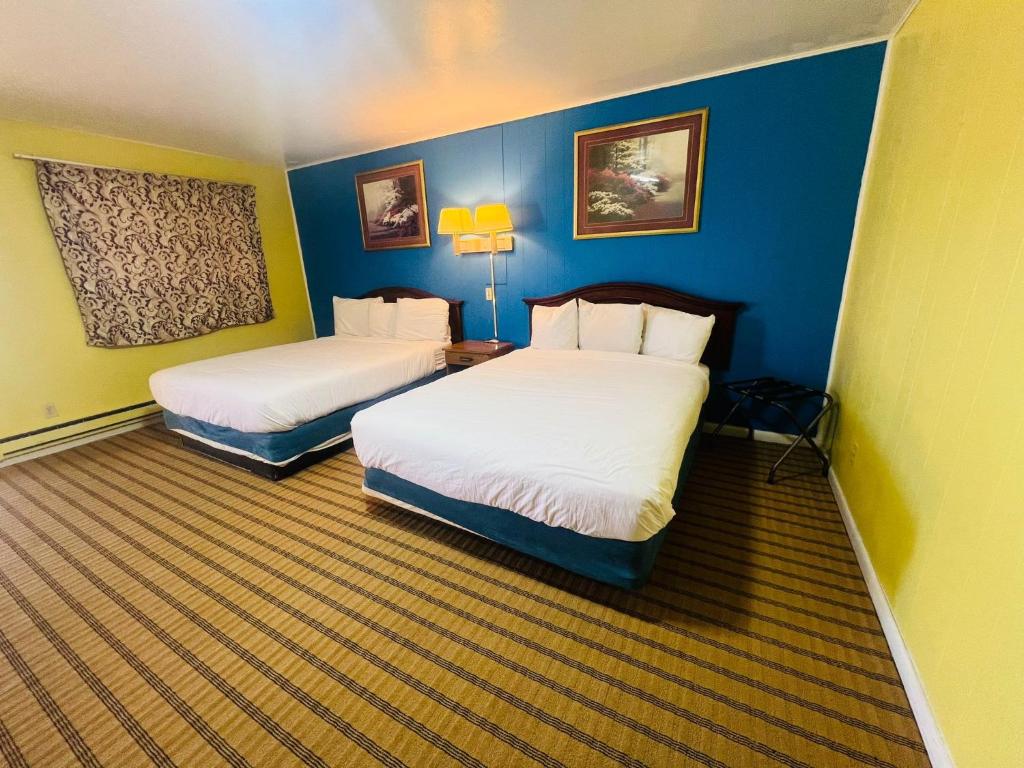 duas camas num quarto de hotel com paredes azuis em Crown Inn em Raton