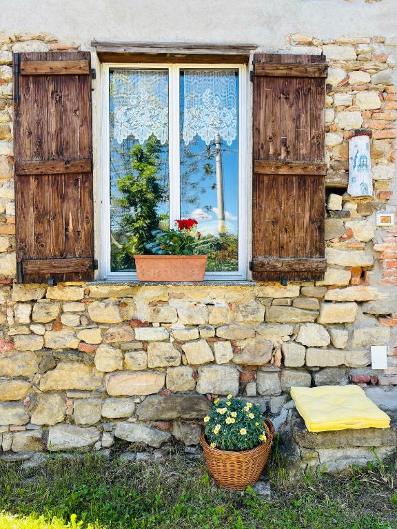 a stone wall with two windows and two potted plants at A casa di Mirna in Borghetto Di Borbera