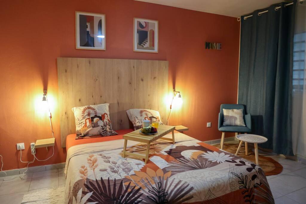 a bedroom with a bed and a table and a chair at Grand studio Bis à Matoury in Matoury