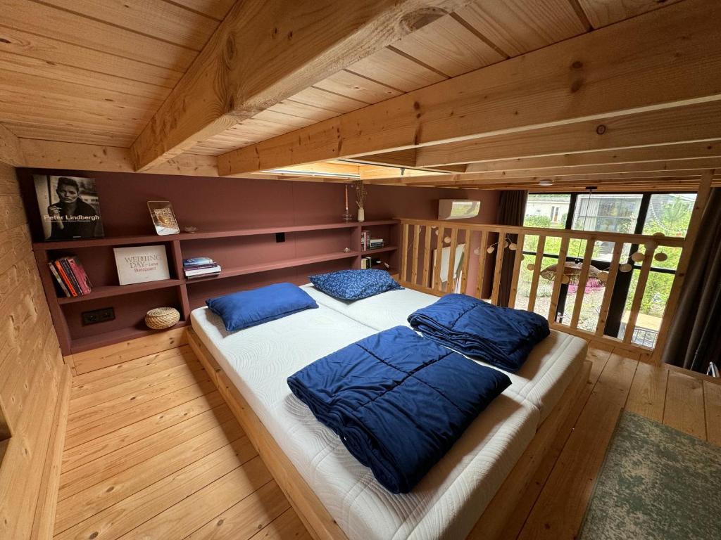 a bedroom with a large bed with blue pillows at Tiny House Mayu - Veluwe Airco 4 persons in Arnhem