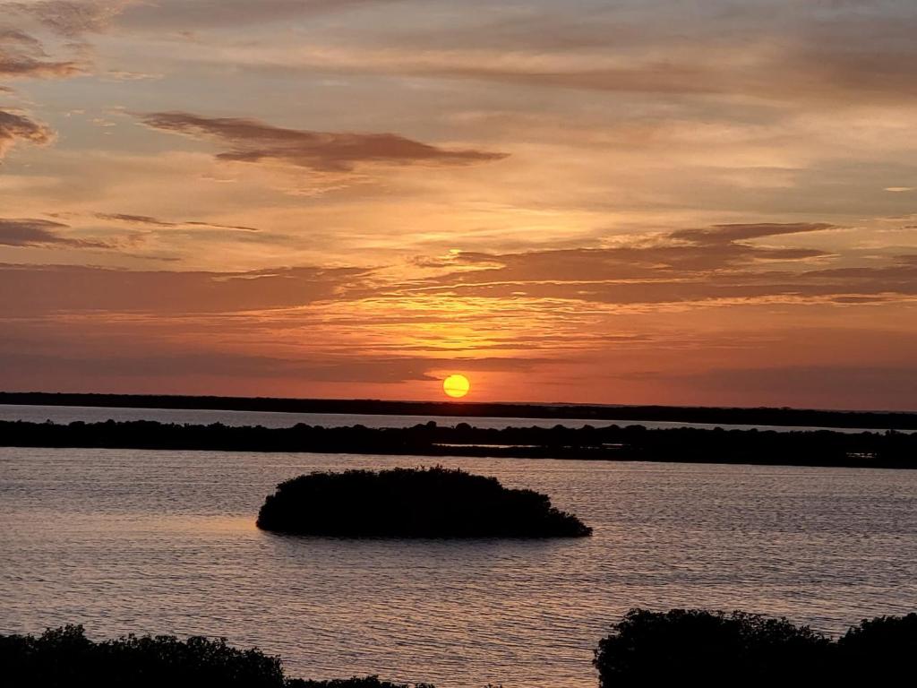 una puesta de sol sobre un cuerpo de agua con una pequeña isla en Coconuts Caribe, en San Pedro