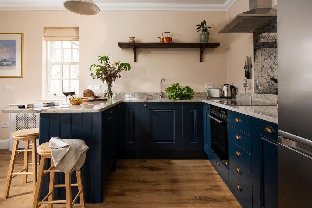 a kitchen with blue cabinets and marble counter tops at Fairnington East Wing in Kelso