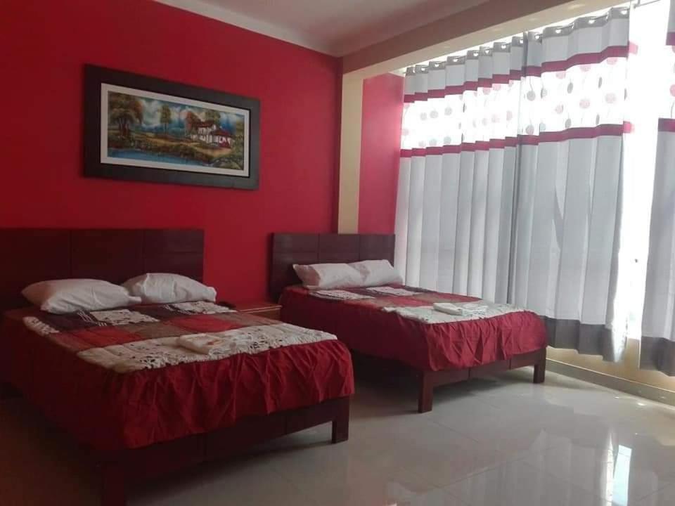 two beds in a room with red walls and windows at Hostal Los Angeles in Tarapoto