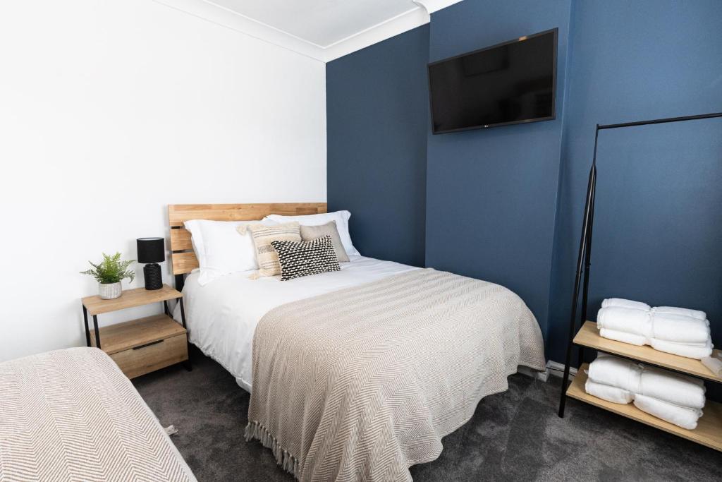 um quarto com uma cama e uma parede azul em Steel Town Lodge - Comfy Home in Port Talbot with Hot Tub, Sky Sports & Dart Board em Port Talbot