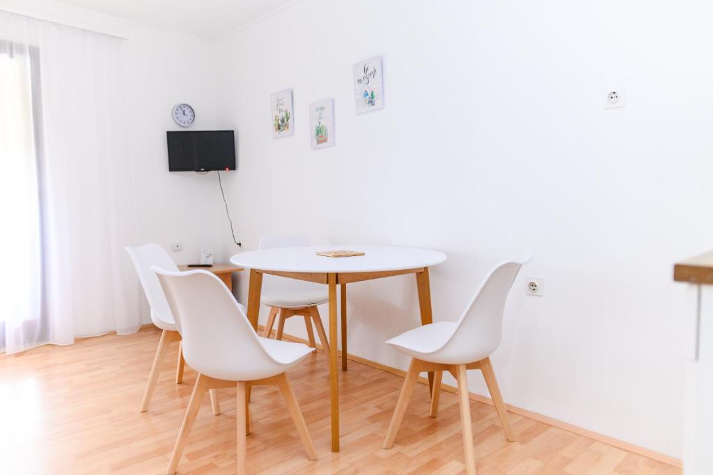 una sala da pranzo con tavolo e sedie bianche di Apartmani Zvirac a Soko Banja