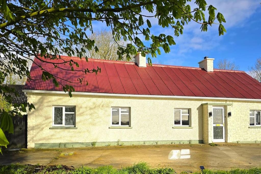 uma casa branca com um telhado vermelho em Cara's Cottage em Kinawley