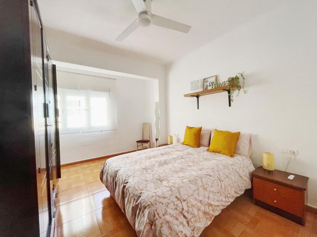 1 dormitorio con 1 cama con almohadas amarillas y ventilador de techo en La Casita de las Hermanas, en Málaga
