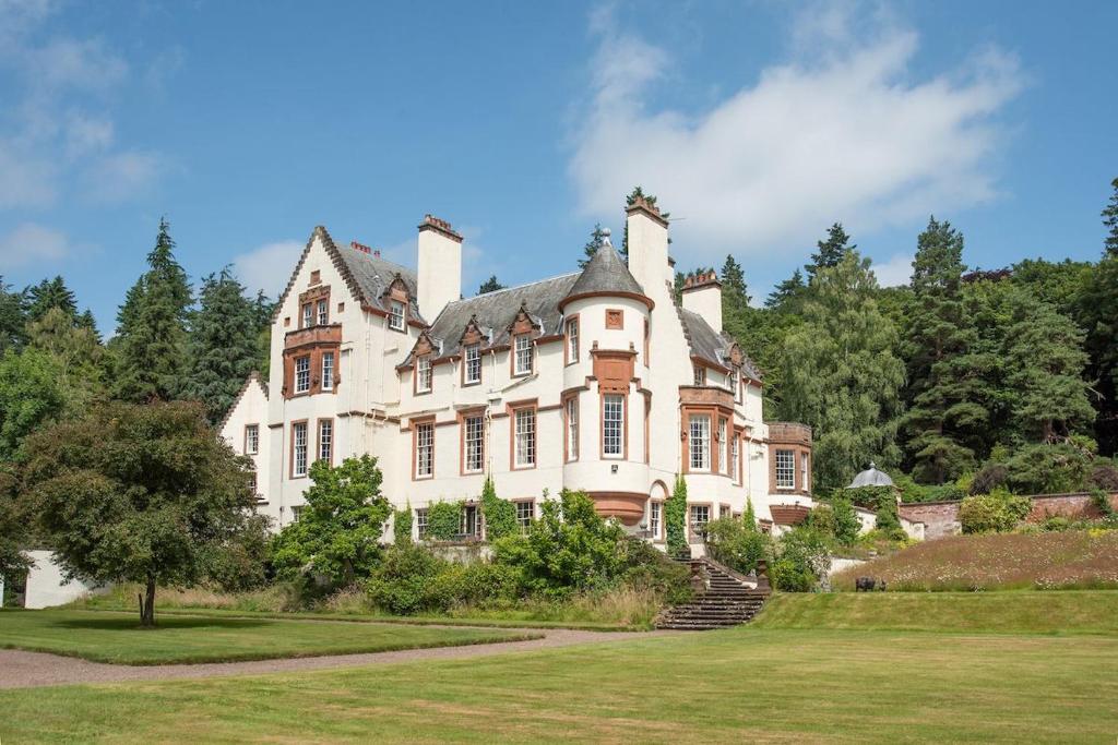 a large white house with trees in the background at Fairnilee House in Galashiels