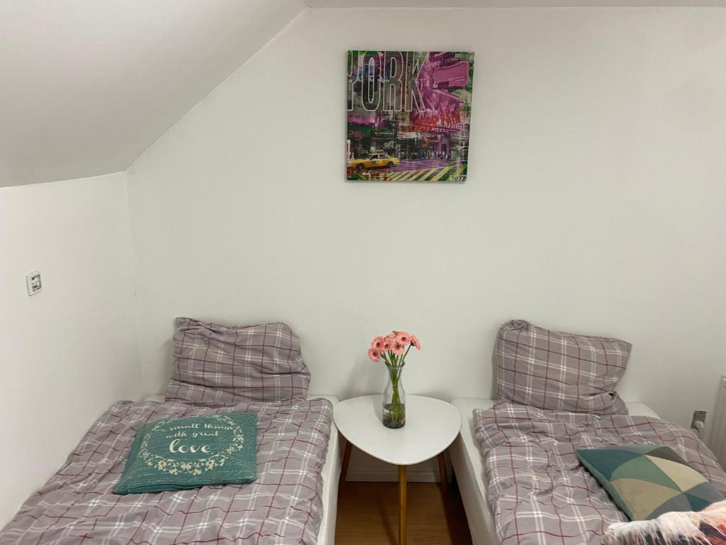 Billund star في بريندا: سريرين في غرفة مع طاولة و مزهرية مع الزهور