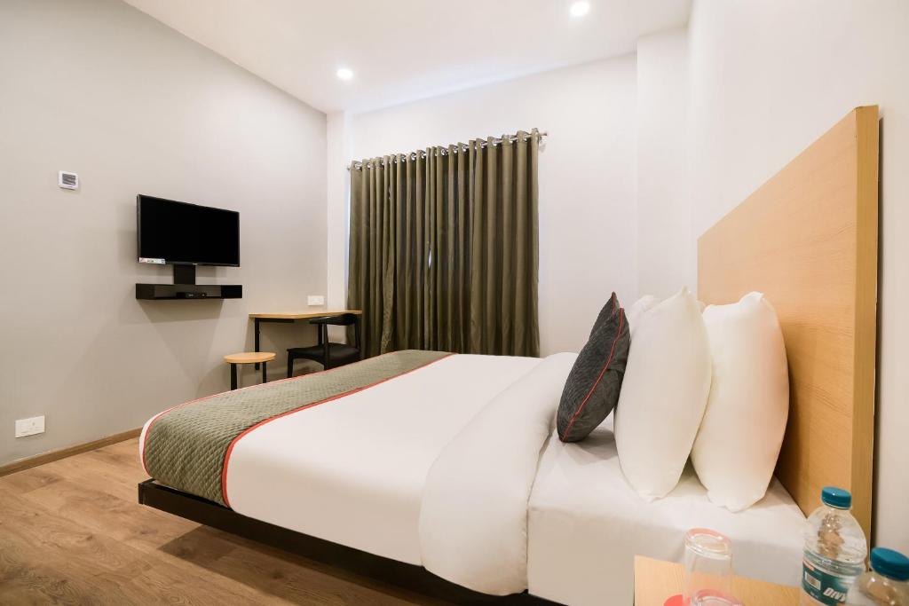 a hotel room with a bed and a television at Super Townhouse 217 The Awadh Airport Near Chaudhary Charan Singh International Airport in Bijnaur