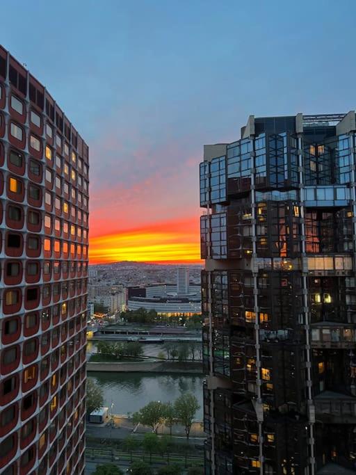 une vue d'un coucher de soleil entre deux grands immeubles dans l'établissement Tour Reflet Paris 15, A cozy and welcoming home, just like your own, à Paris