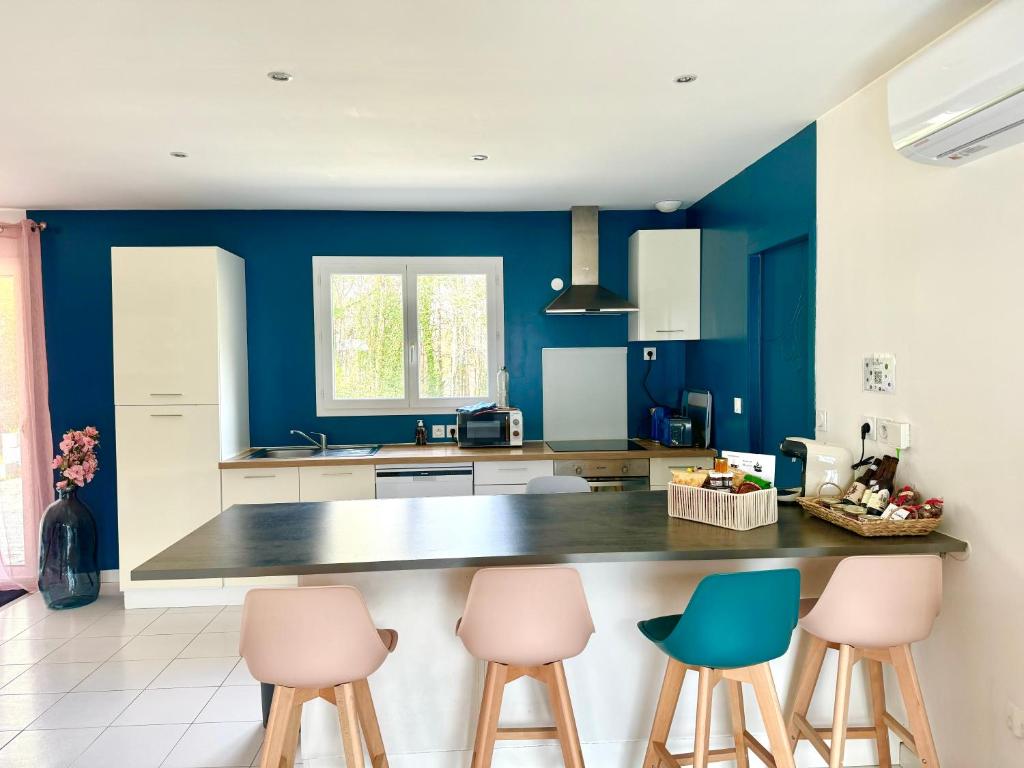 una cucina con pareti blu e bancone con sgabelli di Caporizon -Villa Pommier-6 personnes-Terrasse-Jardin a Crégandie