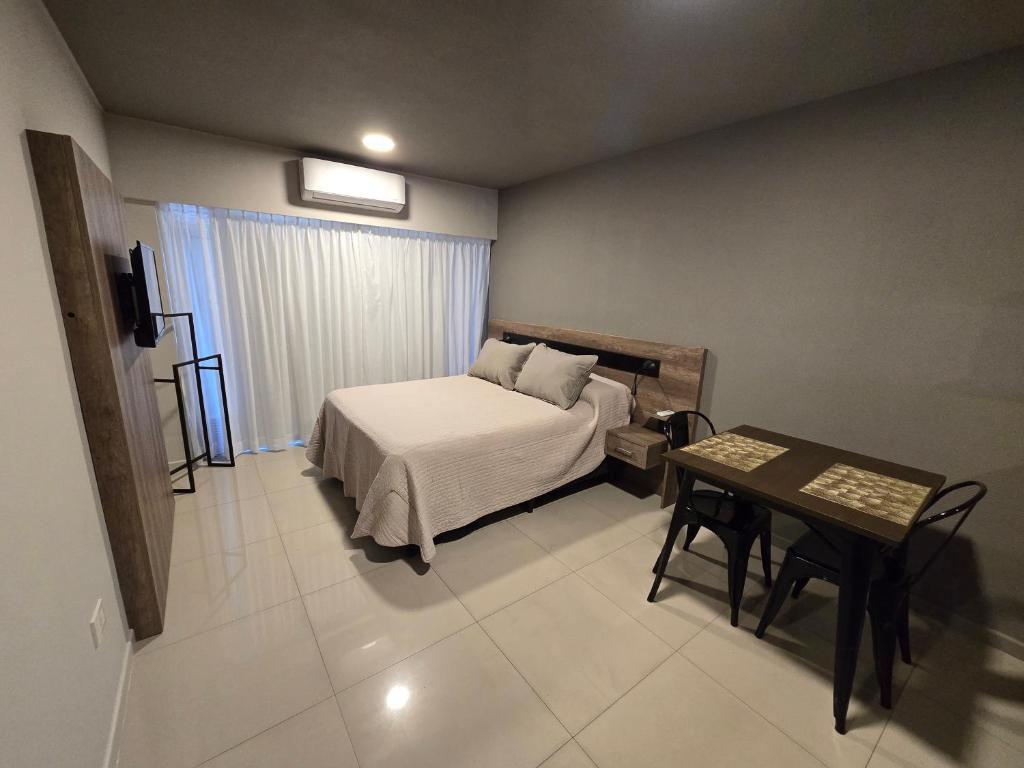 a bedroom with a bed and a table in it at Maipú y Avenida Pellegrini con Parking privado opcional in Rosario