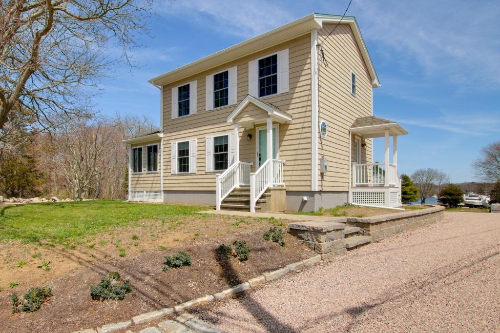 a yellow house with a porch and a driveway at Charming Home with Yard Steps to Pawcatuck River! in Pawcatuck