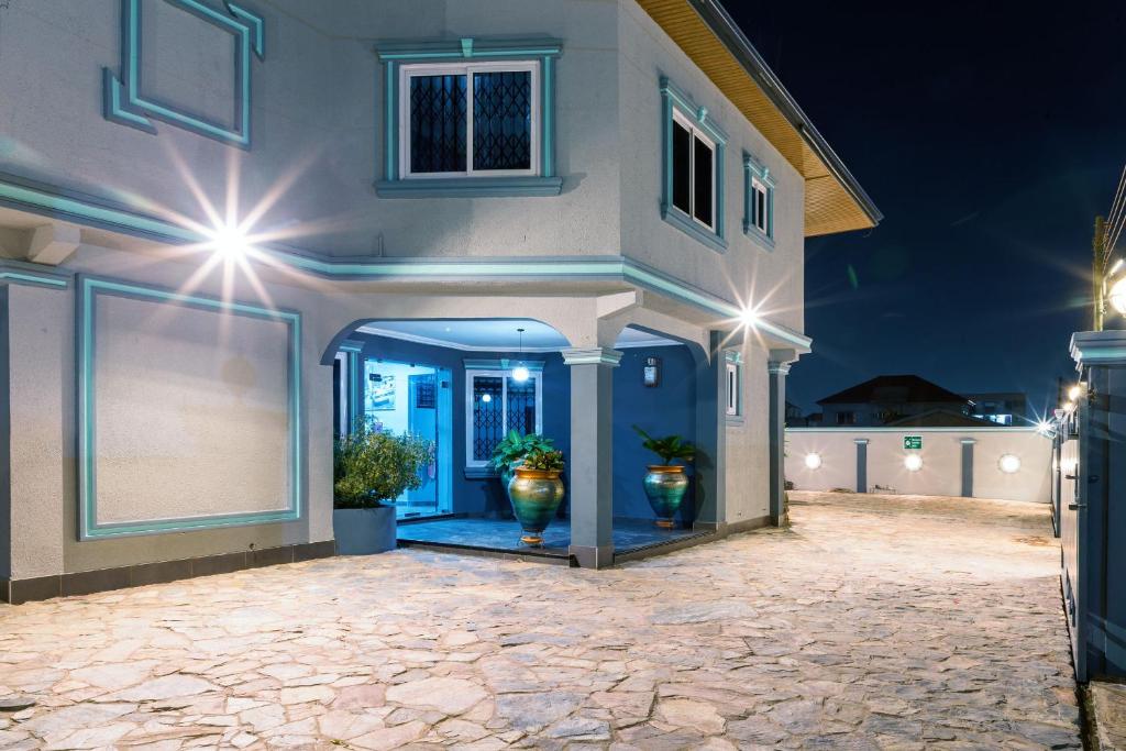 BlueGreen GuestHouse في آكرا: منزل به اثنين من النباتات الفخارية في ممر السيارات في الليل