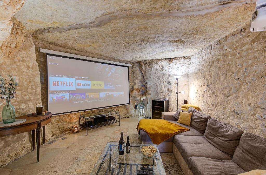 uma sala de estar com um grande ecrã numa parede de pedra em Gîte Le Paul Bert - centre ville-parking gratuit em Tours