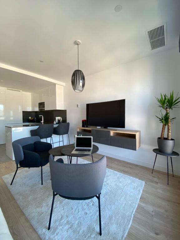 ein Wohnzimmer mit einem Tisch und Stühlen sowie einem TV in der Unterkunft Urban Sky Views over Malaga in Málaga