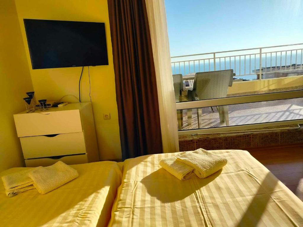 a bedroom with two beds and a balcony with a television at Golden Sea View in Sveti Vlas