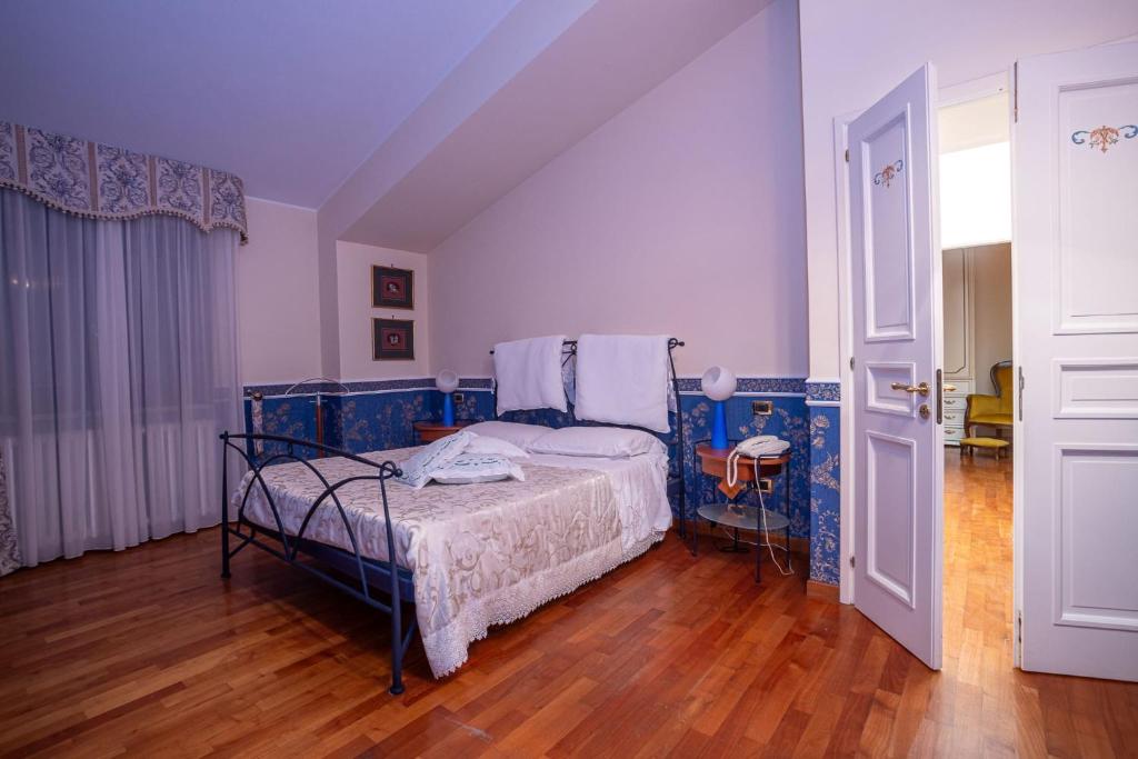 a bedroom with a bed and a wooden floor at Il Giardino dei Tigli Villa Bianco in Rotondi