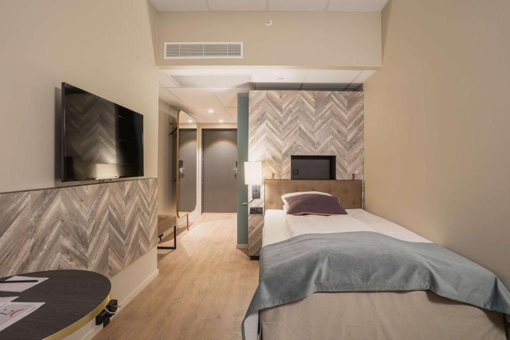 特羅姆瑟的住宿－特羅姆瑟斯堪迪豪華酒店，一间卧室配有一张床和一台平面电视