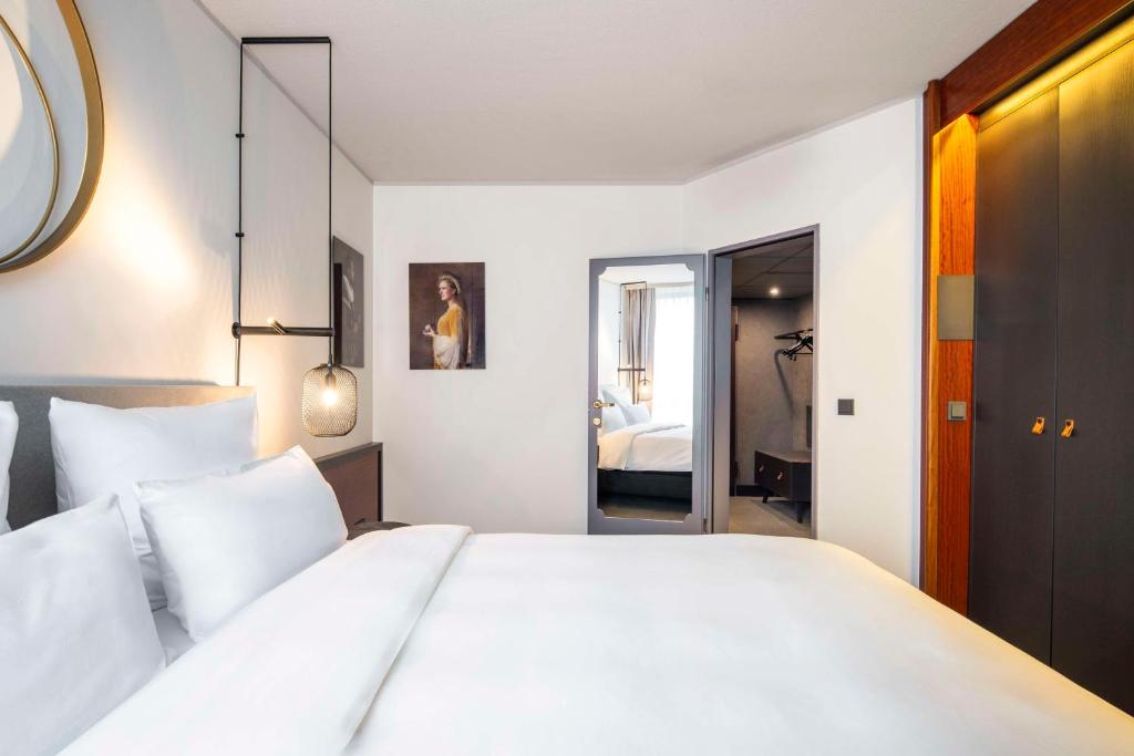 een slaapkamer met een groot wit bed met witte kussens bij Scandic Nürnberg Central in Neurenberg