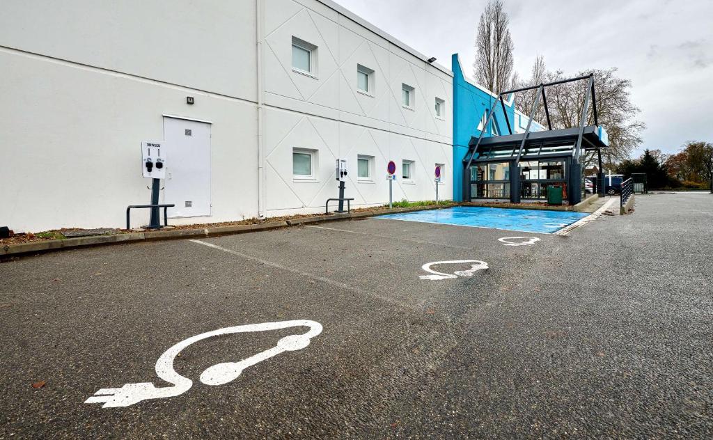pusty parking z budynkiem i basenem w obiekcie Kyriad Direct Moulins Sud - Yzeure w mieście Yzeure