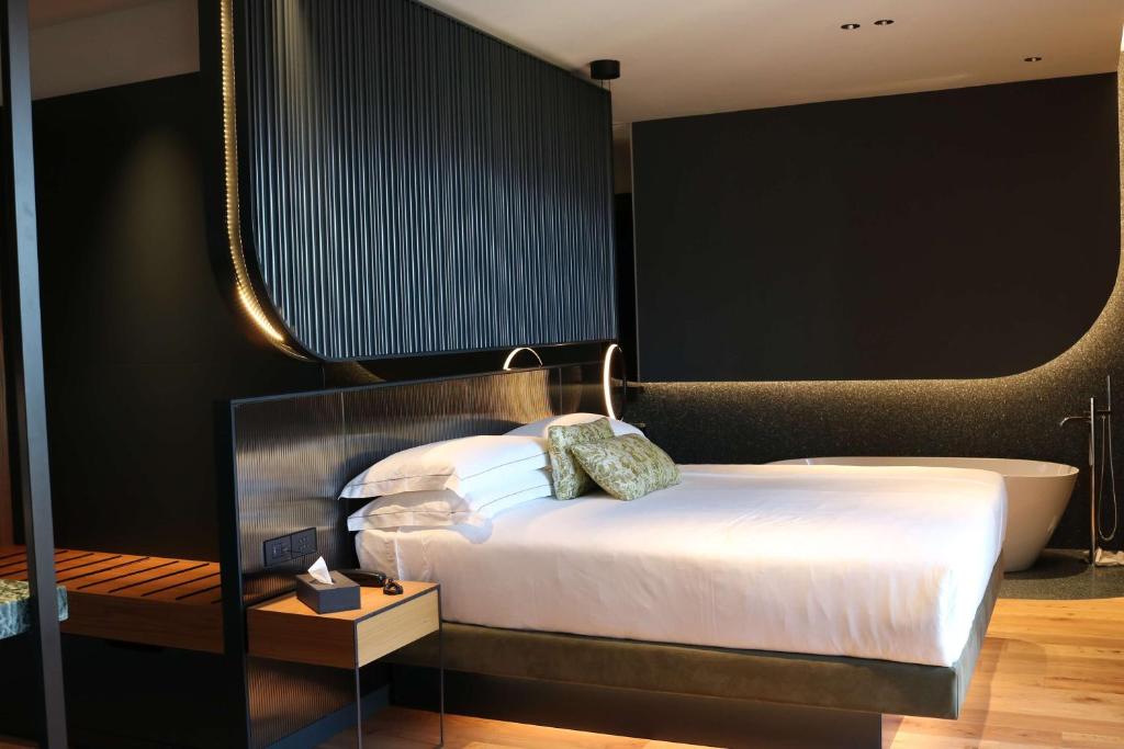 Schlafzimmer mit einem Bett und einer Badewanne in der Unterkunft Hotel Al Caminetto WorldHotels Crafted Adults Only in Torri del Benaco