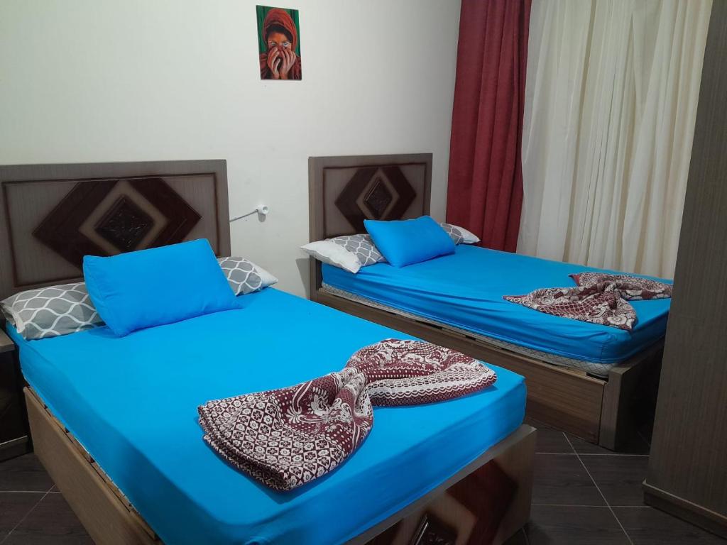two beds with blue sheets in a room at Porto Matroh Tours in Marsa Matruh
