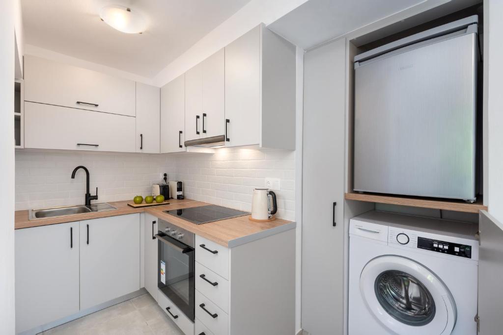 a kitchen with white cabinets and a washer and dryer at GIAMARIN in Istro