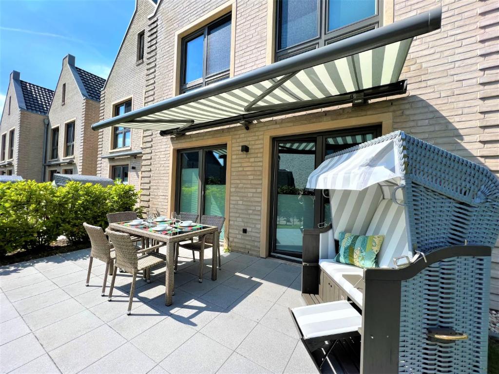 a patio with a table and chairs and a grill at Nordsee Park Haus Friesland 6 P112 in Dangast