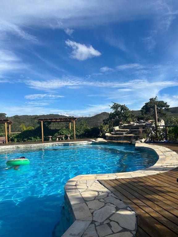 a swimming pool with blue water and a wooden deck at Pousada Serra Morena in Serra do Cipo