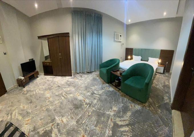 pokój hotelowy z łóżkiem i 2 zielonymi krzesłami w obiekcie أضواء الشرق للشقق الفندقية Adwaa Al Sharq Hotel Apartments w mieście Sīdī Ḩamzah