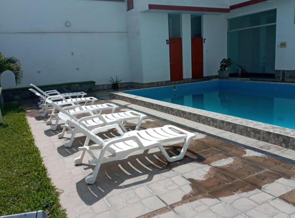 a row of lounge chairs next to a swimming pool at Descanso de Vallecito in Hacienda Huampani