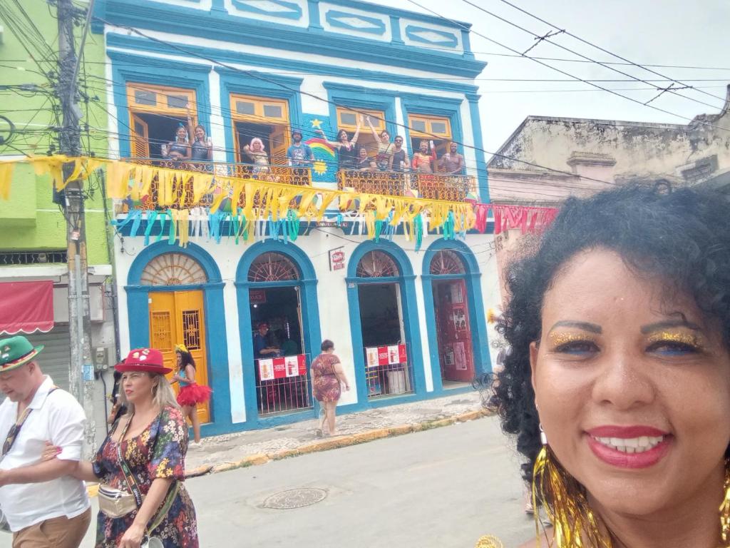 uma mulher em pé em frente a um edifício azul em Casa do Carnaval em Olinda