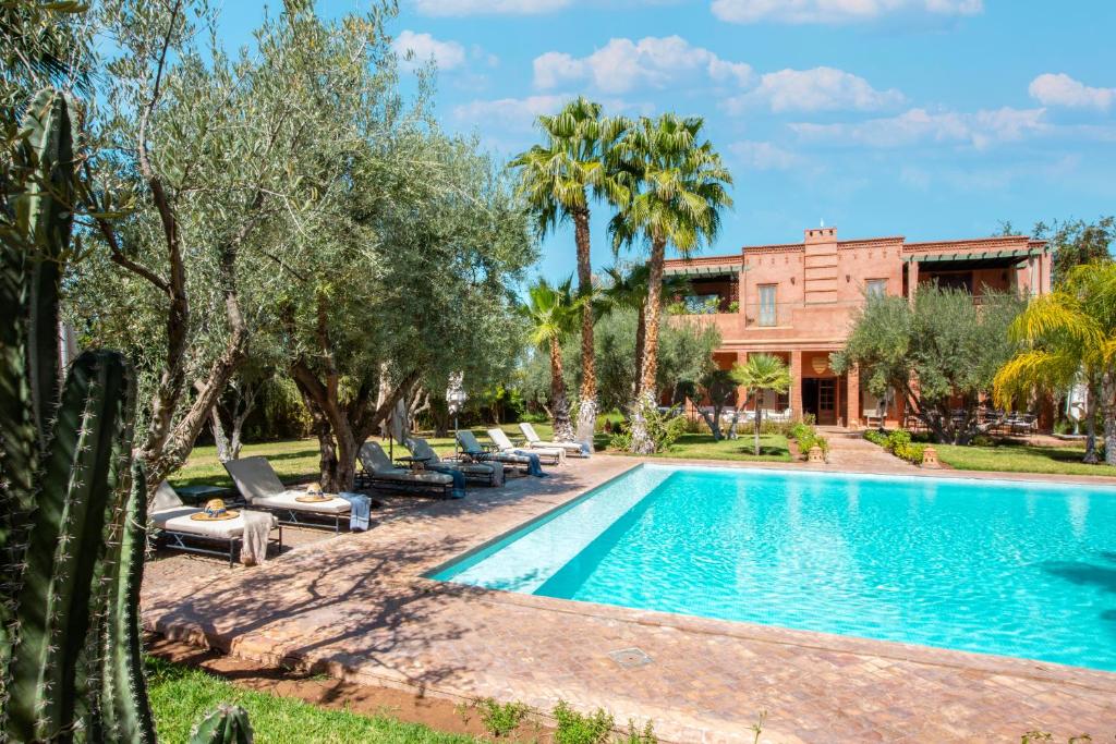 una piscina frente a una casa con palmeras en Moroccan sumptuousness, 6 bedroom Riad - by feelluxuryholidays, en Marrakech