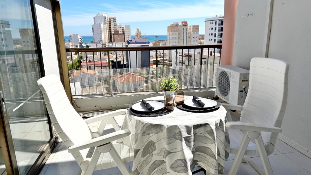 a table and two white chairs on a balcony at REYNA Playa de Gandía - Alquiler solo a familias in Los Mártires