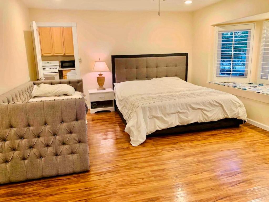um quarto com uma cama, um sofá e pisos em madeira em Spacious & Pet Friendly Oceanside Home em Oceanside