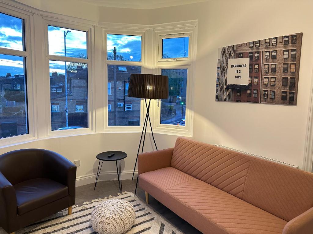 a living room with a couch and a chair and windows at BRAND NEW!! Startlet Stays Apartments - On Elizabeth Line in London