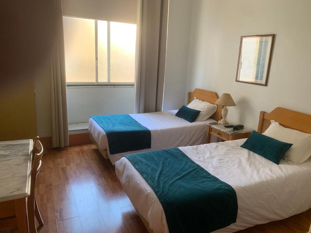 a hotel room with two beds and a window at Residencial Roxi in Lisbon